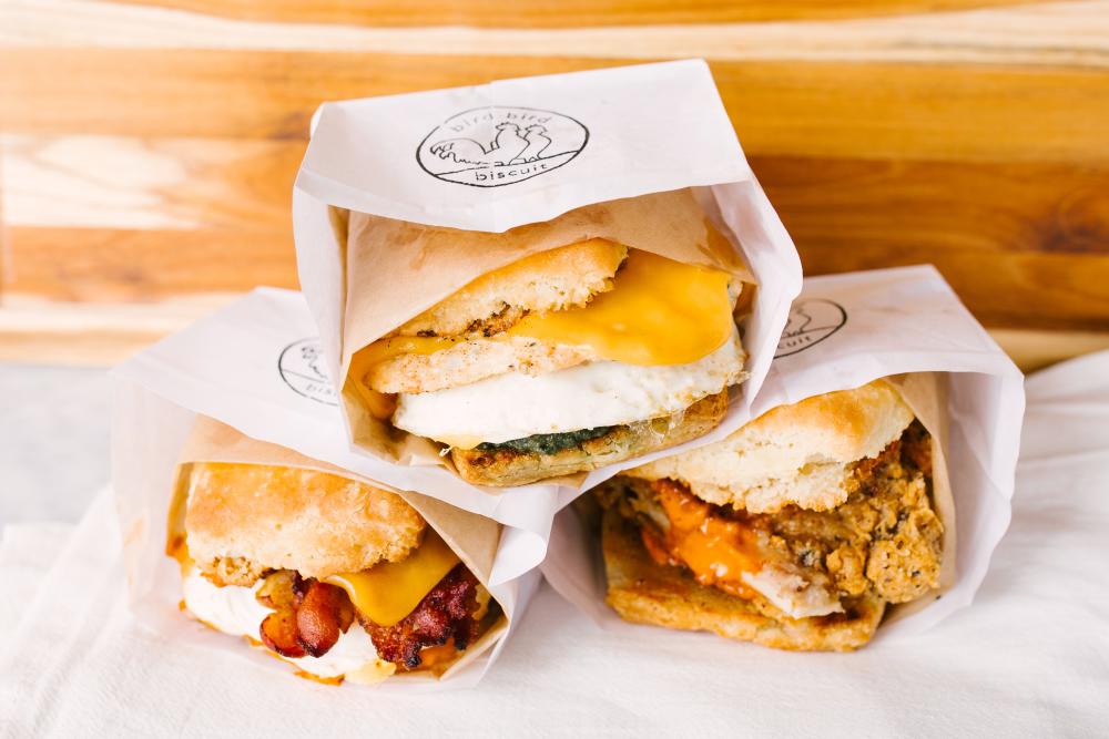 three biscuits in takeout bags from Bird Bird Biscuit in Austin Texas