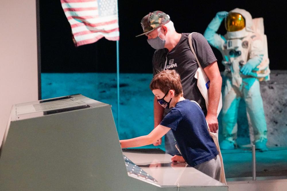 Father and son interacting with space exhibit at Bullock Museum.