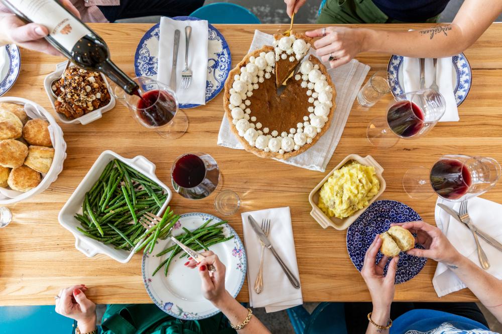 Family style table spread with wine and green beans and pie at Colleens Kitchen in Austin Texas