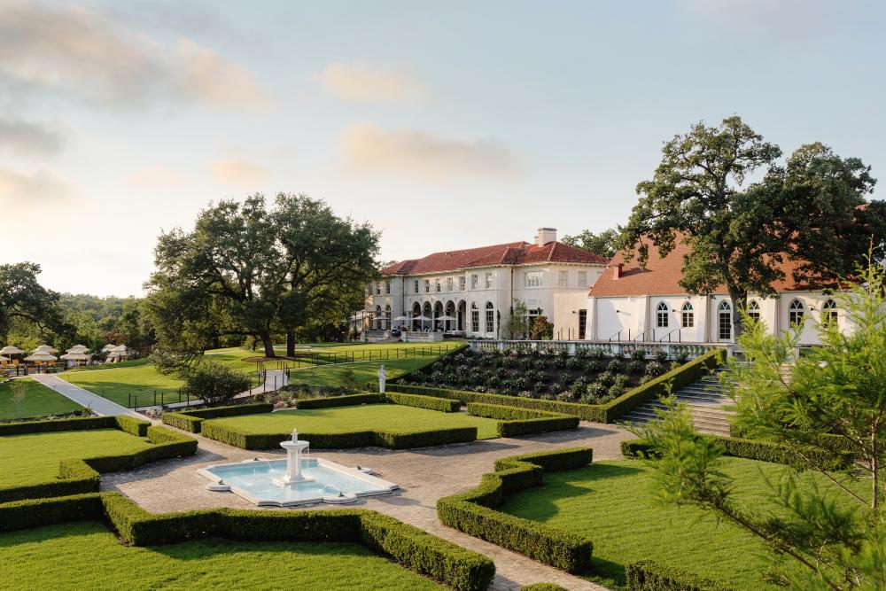 Limestone exterior and grounds at Commodore Perry Estate. There is a water fountain and hedges in the foreground