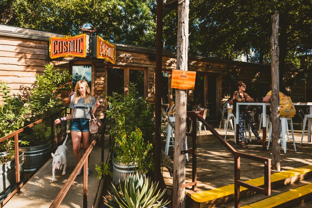 Woman walks down the ramp with a dog outside Cosmic Coffee and Beer Garden in Austin Texas