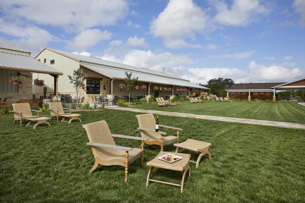 Photo of the Pavilion Lawn at Carter Creek Winery Resort & Spa with wooden chairs in the front and footrests and a plate of charcuteries and bottle of wine