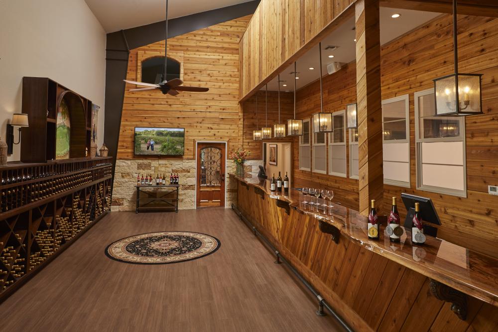 Photo of wooden winery bar at Carter Creek Winery Resort & Spa with bottles on wine on the bar, and racks of wines across from the bar