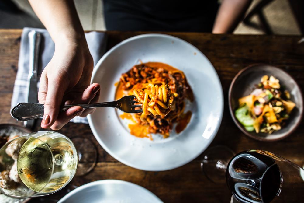 woman holds up fork with spaghetti at Olive and June in Austin Texas