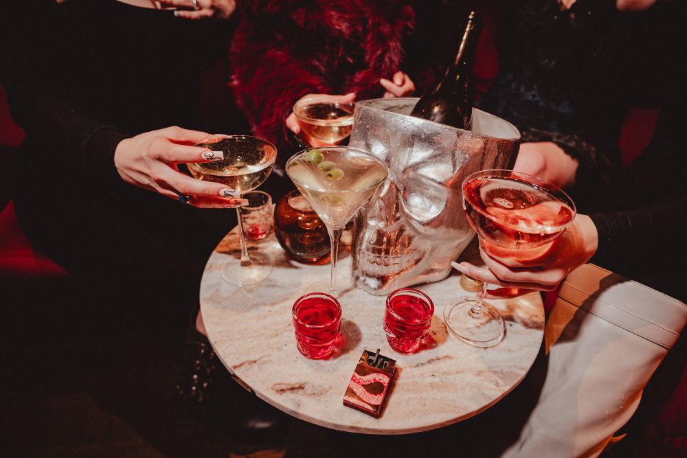 Image of a side table at Revenge Bar filled with different cocktails and an ice bucket shaped like a skull.