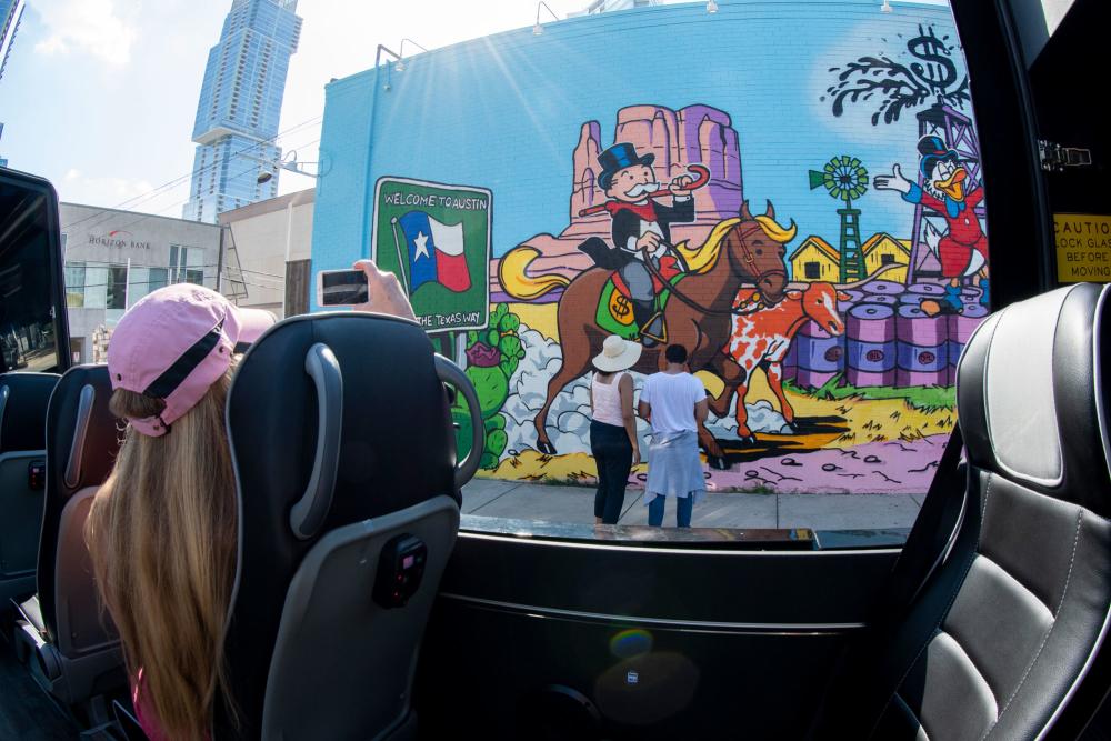 Photo from the inside of the AO Tours open sided Pano-van looking towards a man and woman looking at a mural
