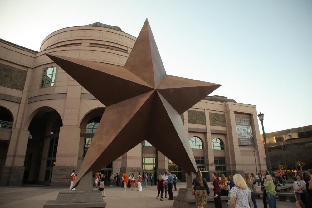 Exterior plaza of the Bullock Texas State History Museum, with the iconic giant Texas star, and conference attendees scattered about.