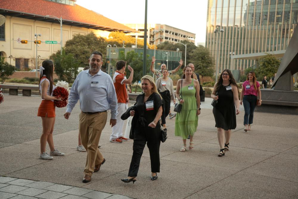 Conference attendees excitedly walking into the Bullock Museum while being cheered on by University of Texas cheerleaders.