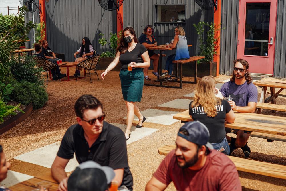 People drinking in outdoor Whiskey Garden at Still Austin Whiskey Co in Austin Texas