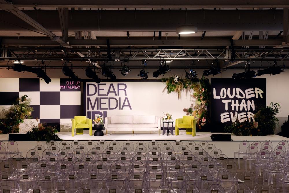 Event venue Brazos Hall set up for an event with decorated stage and lounge seating, and hundreds of neatly lined acrylic audience chairs.