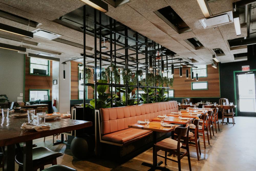Image of a dining room with earthy color tones and tables topped with plates and napkins ready for dinner service.