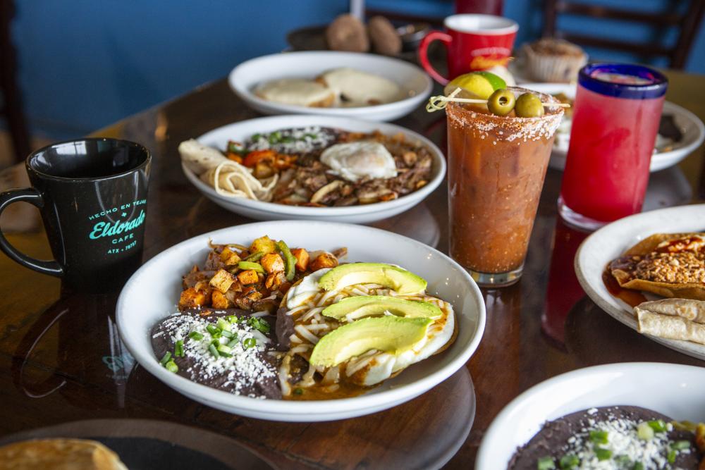 Mexican dishes and cocktails sitting on a wooden table at Eldorado Cafe.