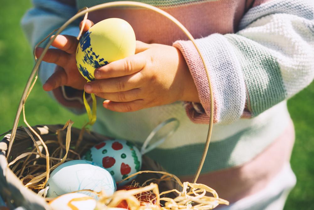 Small child holding an Easter basket and Easter egg.