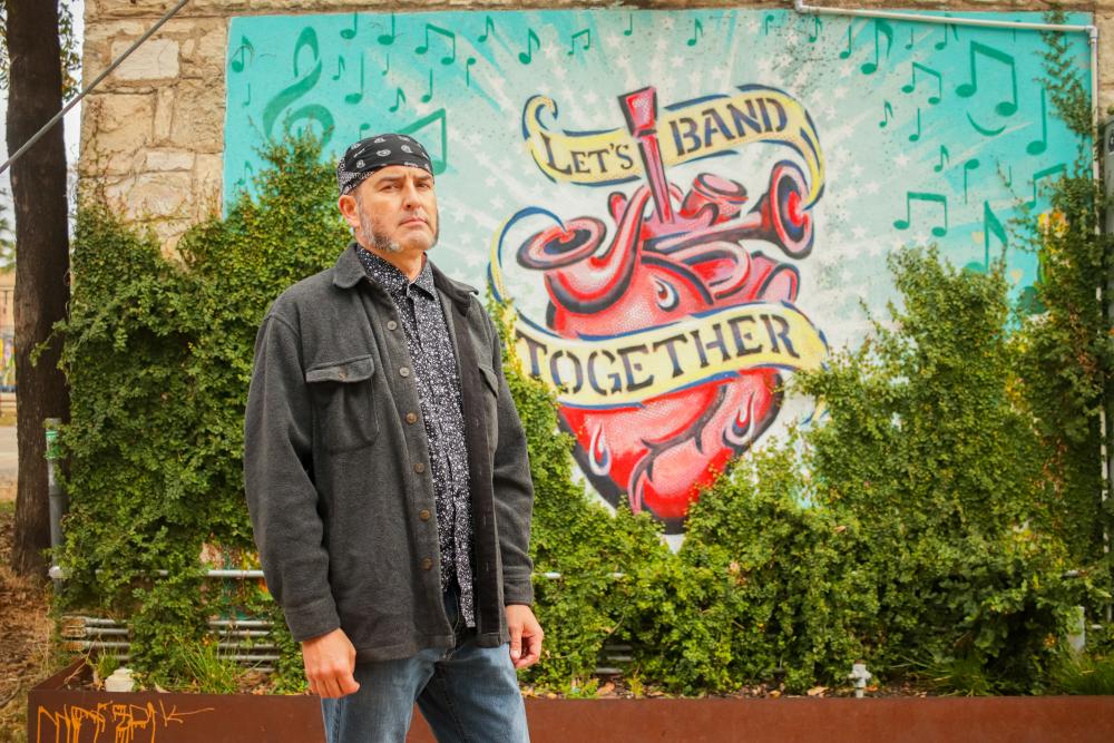 artist Federico Archuleta in front of his mural called Lets Band Together