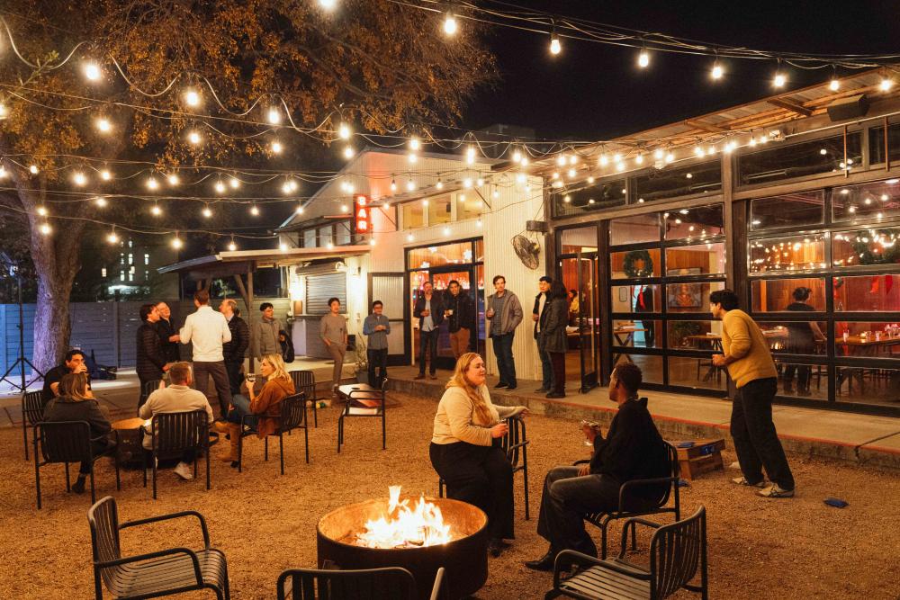 People sitting outside around fire pits on the patio at Franklin Backyard.