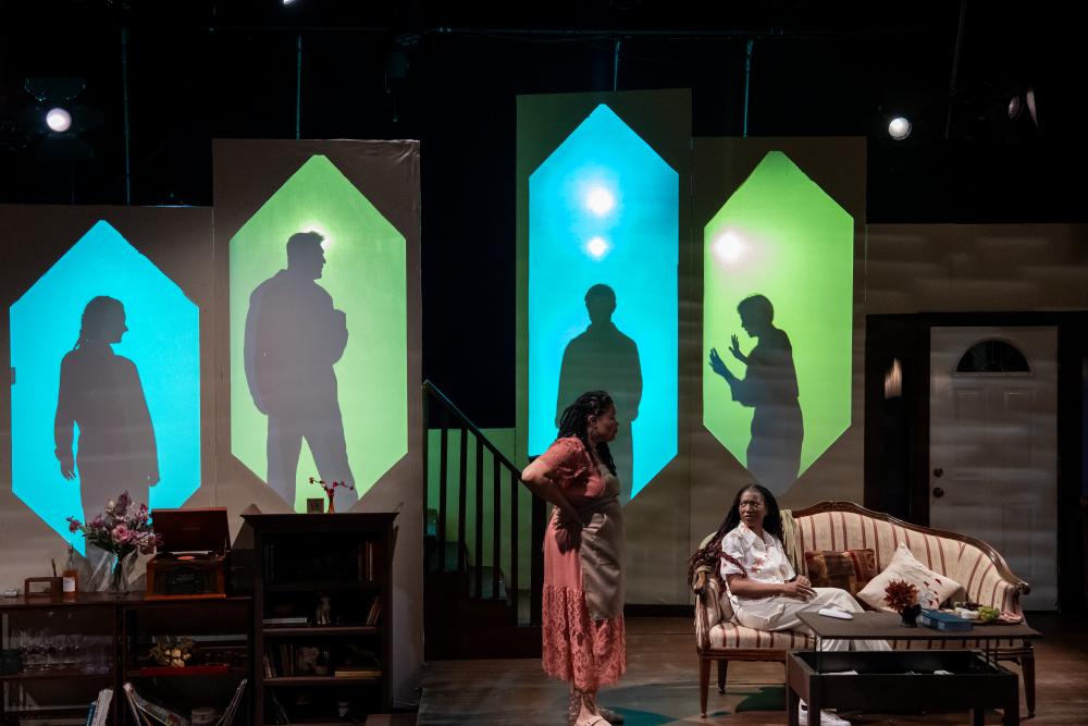 Two women standing on a theater stage acting in a play.