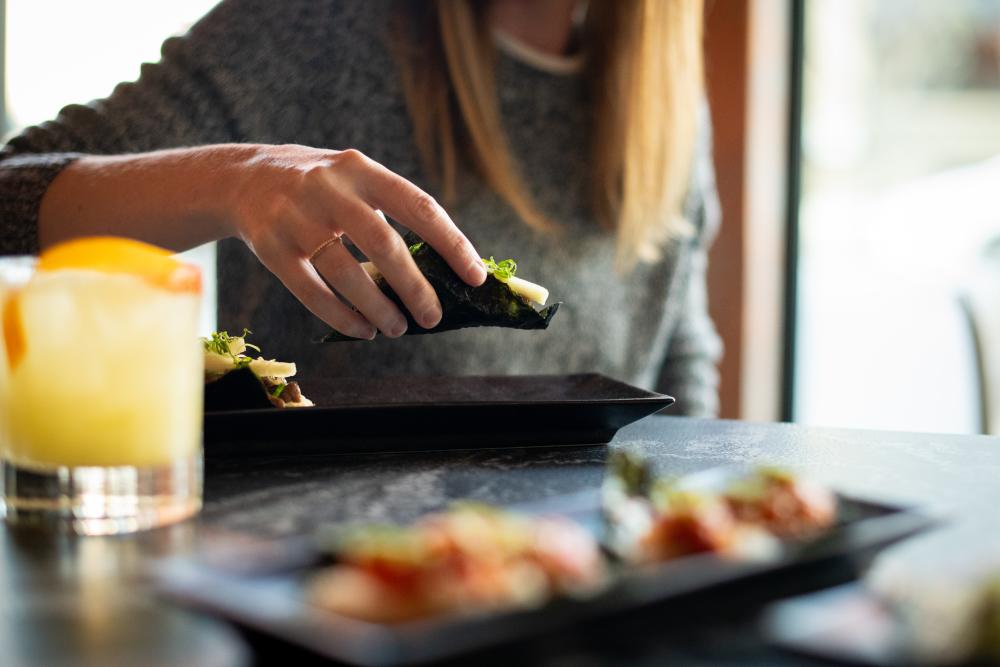 woman eating roll and cocktail from TenTen in Austin Texas