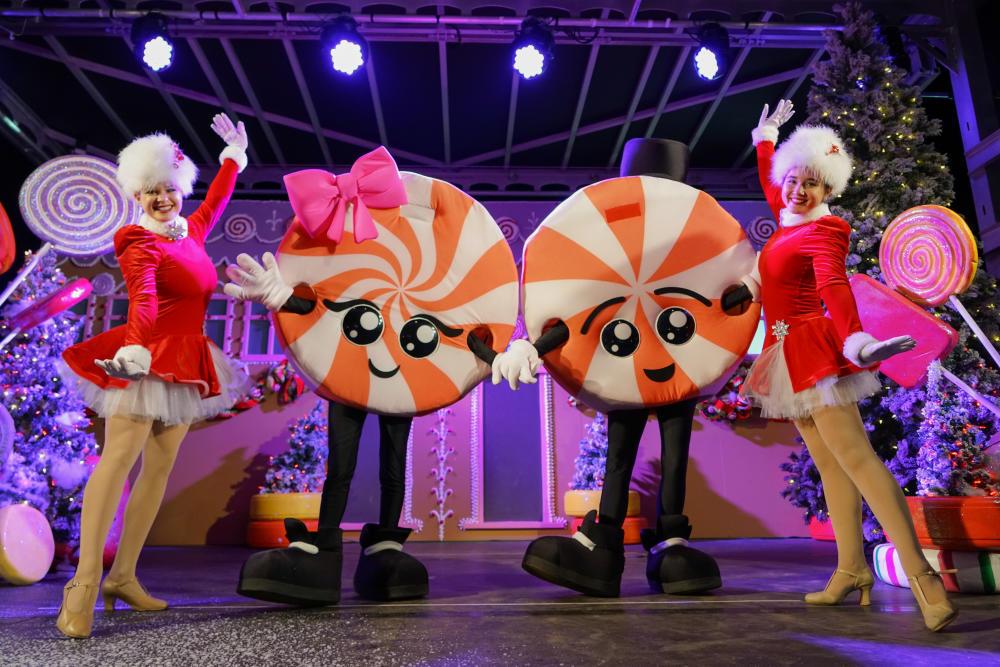 Peppermint Parkway dancers standing next to "Pepper" and "Mint", two swirled peppermint mascots who guide you through the Peppermint Parkway experience.