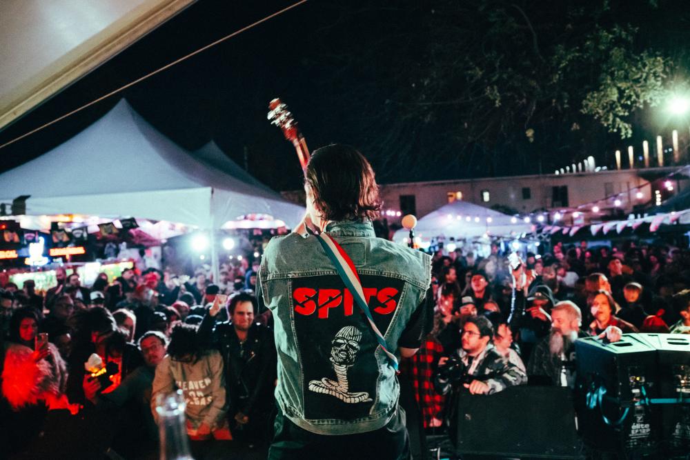 A man performing on stage at Hotel Vegas with the crowd out in front of him listening.