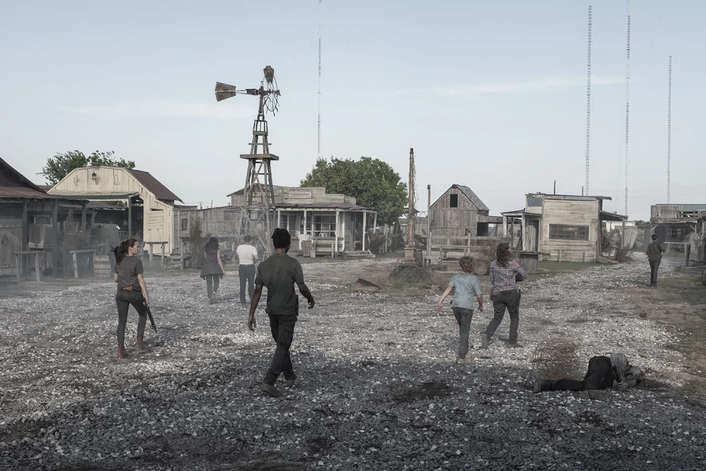 Fear the Walking Dead screengrab showing another angle on the western town set as Humbug's Gulch. Seven characters walk down a gravel covered street dusty street surrounded by old buildings.