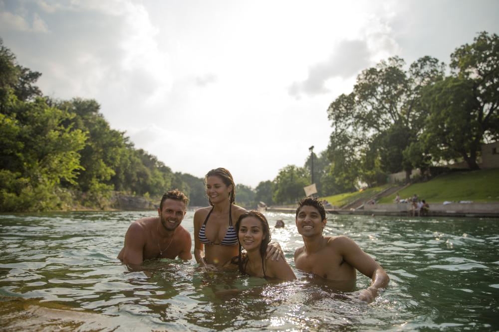 Four people swimming in Barton Springs Pool In Austin, TX