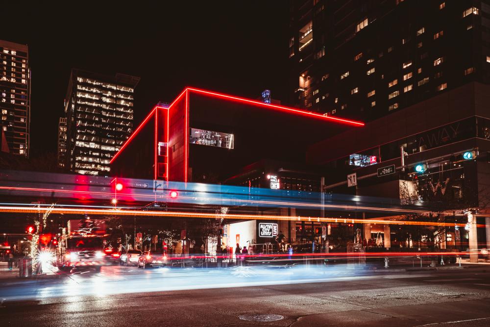 Extierior of ACL Live at the Moody Theater lined by red neon lights, illuminated by blurs of light on the street below.