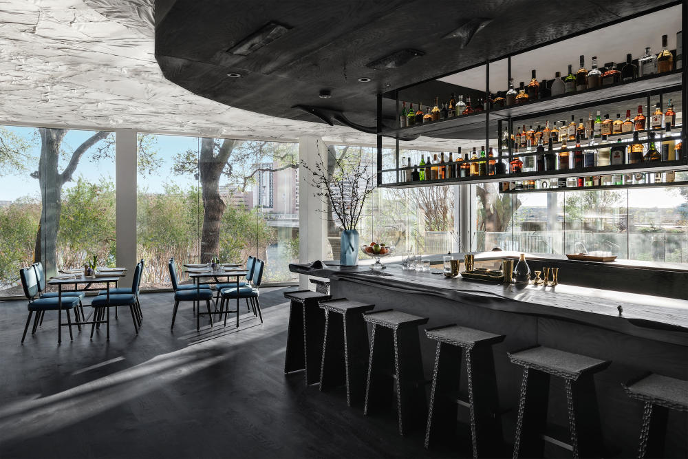 Monocrome bar with restaurant tables and floor to ceiling windows in the background.