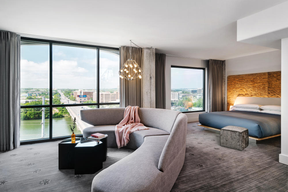 Large, modern hotel room with floor to ceiling windows overlooking Congress Avenue Bridge.