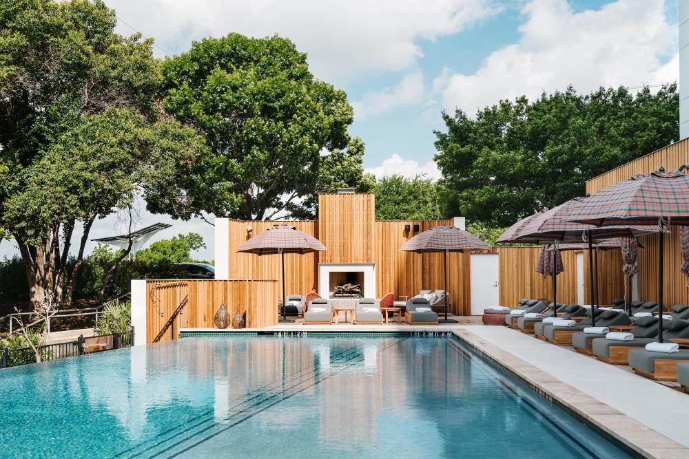 outdoor pool at the LINE Austin hotel with a fireplace and lounge chairs