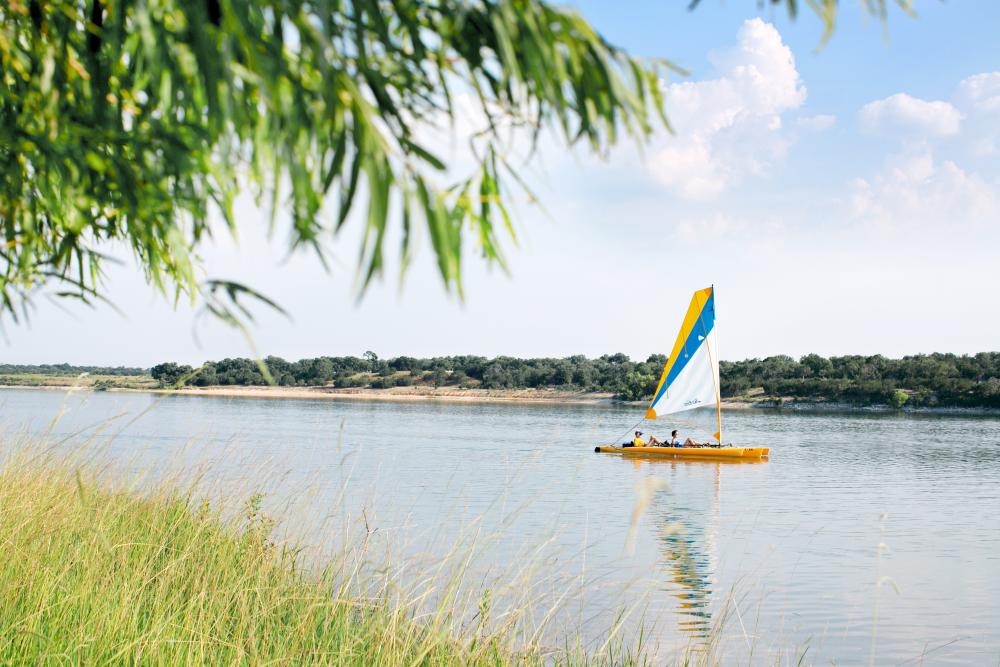 Photo of a sailboat on Boerne City Lake, viewed from the shoreline in Boerne Texas