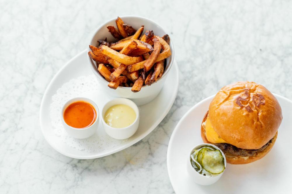 Plancha burger with fries and three side sauces at Launderette in Austin Texas