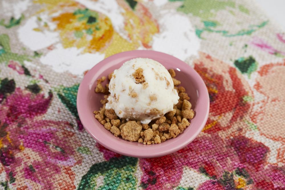 Lick Honest Ice Creams seasonal Lady Bird lavender flavor ice cream with crispy gram cracker crumbs, sitting in a pink bowl on a floral table cloth.