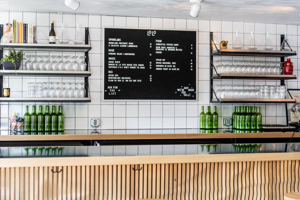 Bar with neatly stacked glassware and a menu board of wines.