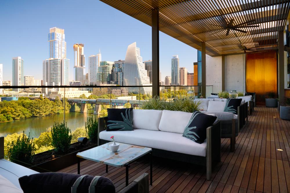 Outdoor lounge chairs on a rooftop patio overlooking downtown Austin and Lady Bird Lake.