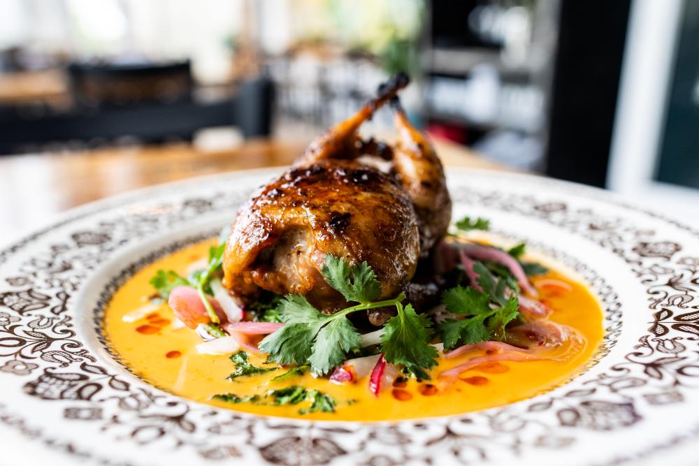A small whole baked chicken plated nicely on a table at Odd Duck.