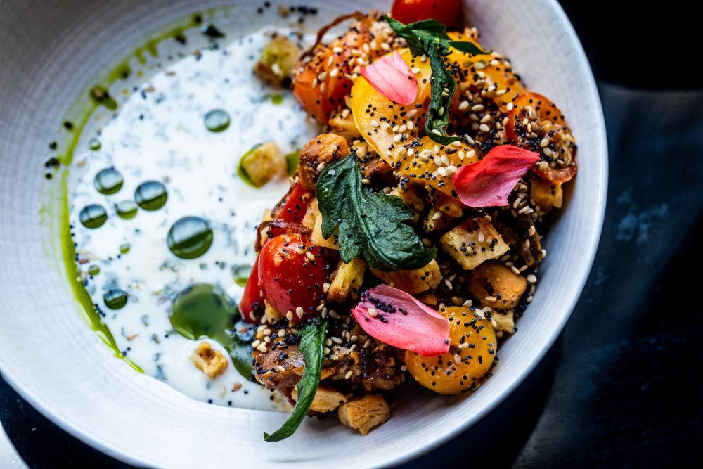 Image of a meal at Olamaie with chicken and vegetables sitting on top of a white sauce.