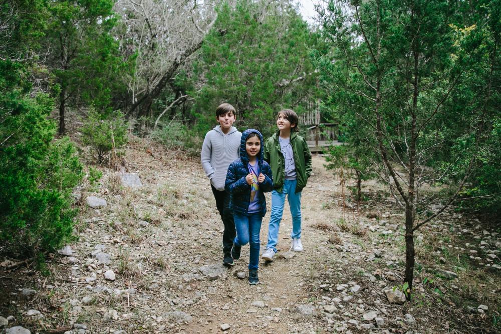 Family of kids walking through a nature trail in the Austin Barton Creek Greenbelt.