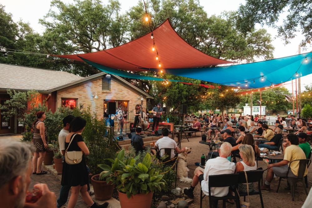 Photo of people sitting on at outdoor patio at Radio Coffee & Beer watching a live band performing on stage.