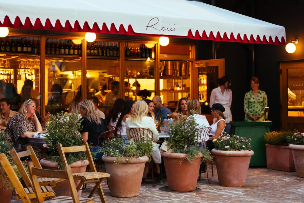 People sitting on a patio of what looks like a French bistro.