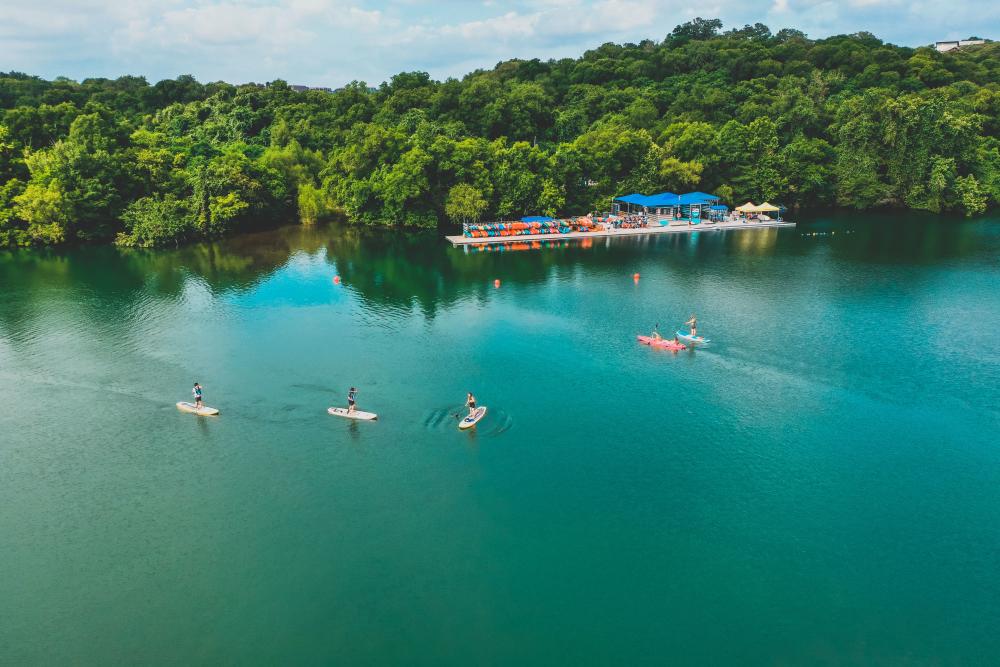 Aerial photo of people using kayak and paddle board rentals from Rowing Dock's shop on the shoreline of Lady Bird Lake Rowing Dock in Austin Texas