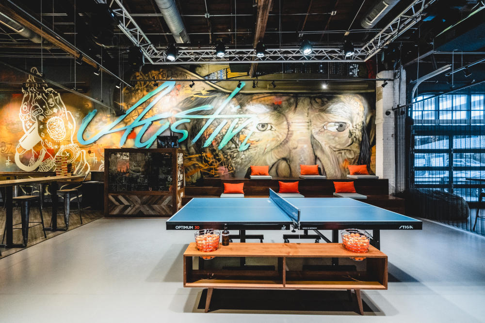 Smash ATX's center ping pong table with Austin mural in the background.