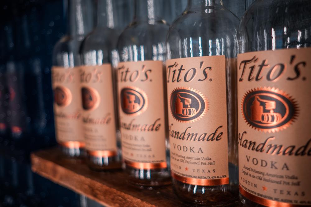 Five bottles of Tito's handmade vodka lined up on shelf
