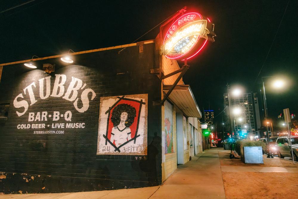 Image of the exterior of Stubb's and the illuminated neon Red River sign.