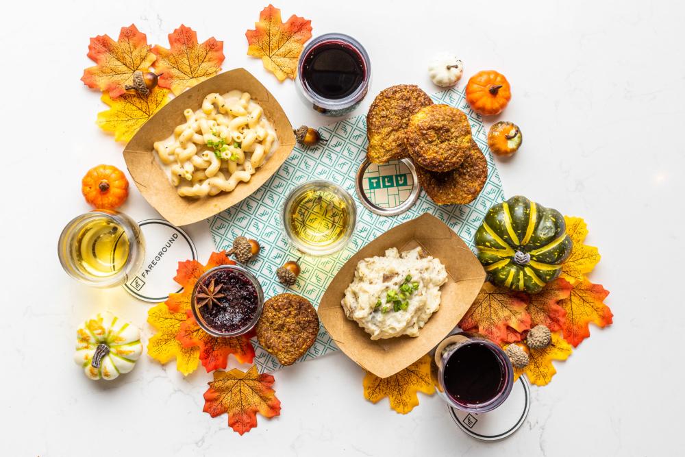 Spread of thanksgiving side dishes mixed in with scattered fall leaves and pumpkins on a white background.