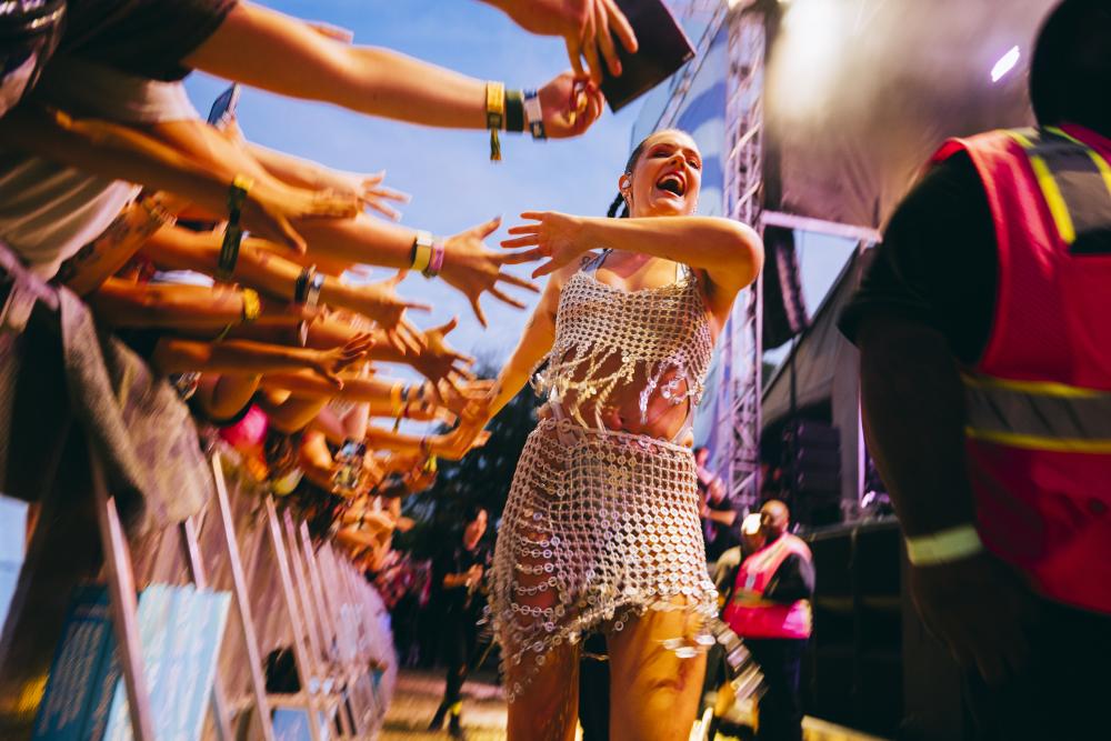 Tove Lo walking past fan barricades high-fiving fans' outstretched arms.