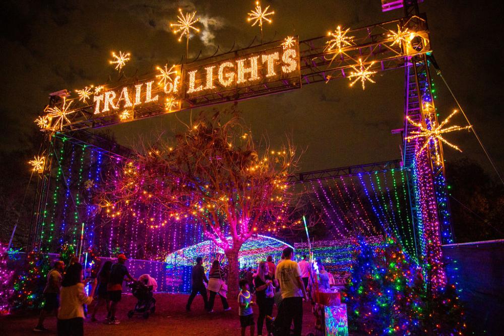 Image from a low perspective of the large illuminated sign stating "Trail of Lights" at the entrance to the event.