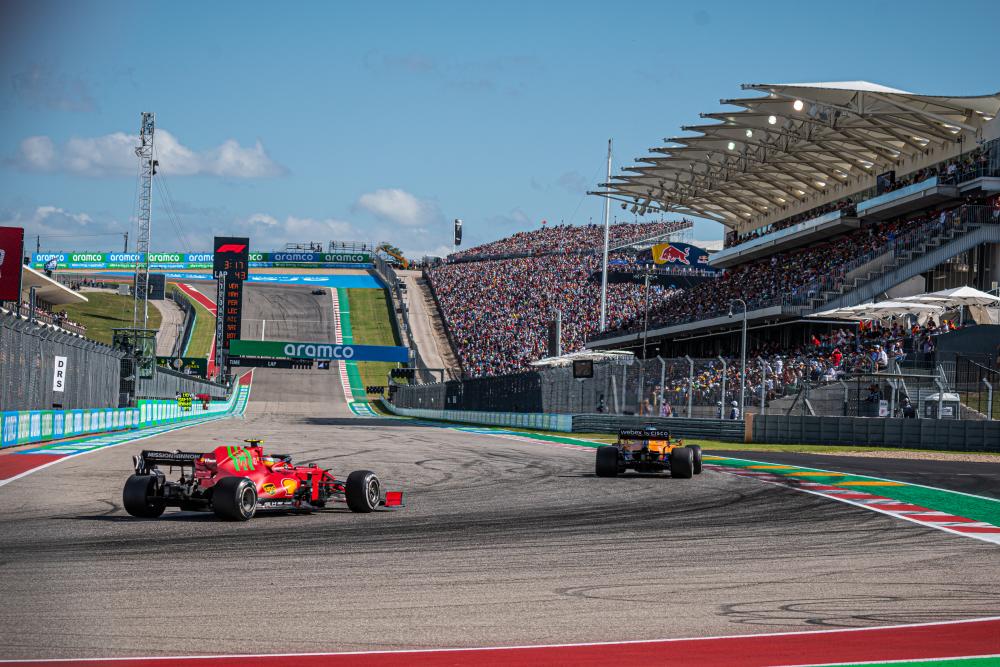 Two formula one cars round the turn in front of fan stands at Austins Circuit of The Americas racetrack