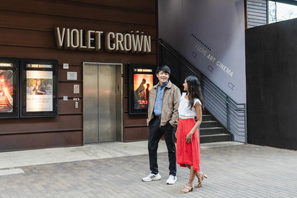 Man and woman holding hands while walking past the entrance of the Violet Crown Theatre in Austin's 2ND Street District.