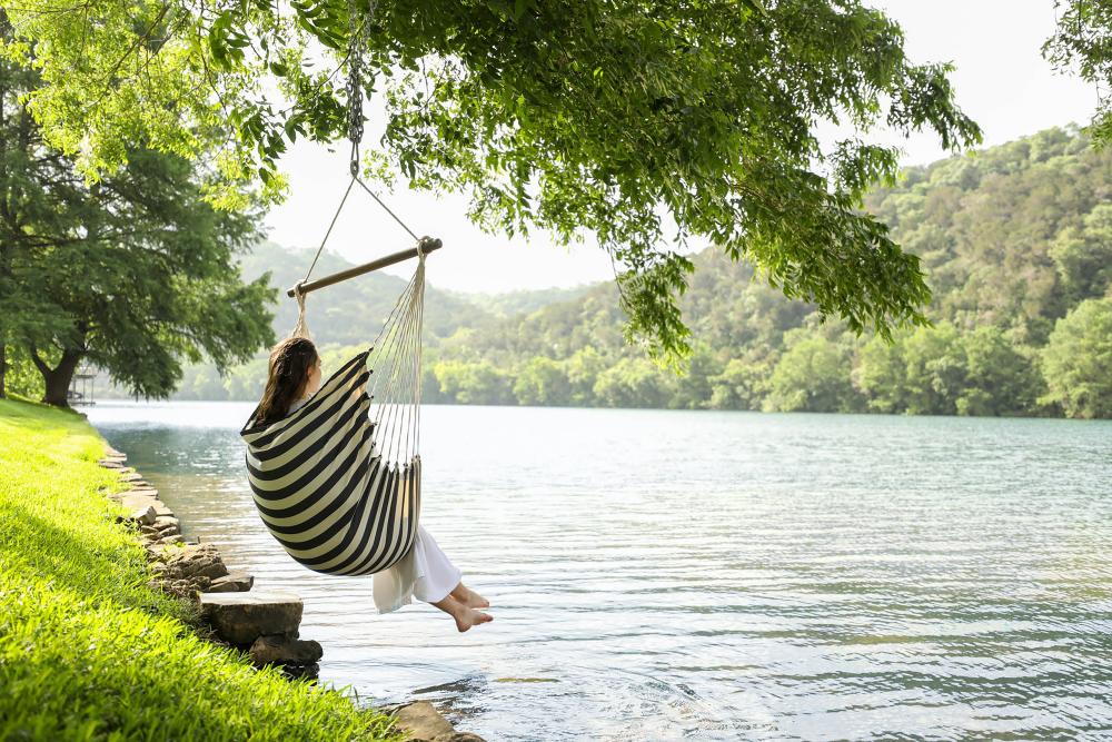 Woman sitting in hammock over the Lake at Lake Austin Spa Resort in Austin Texas