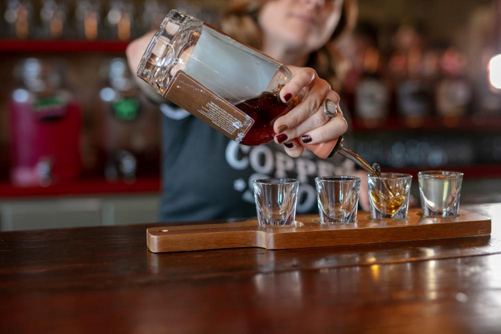 A bartender pouring liquor into shot glasses.